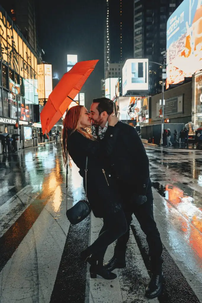 cute couple kissing in the rain using an umbrella against the rain