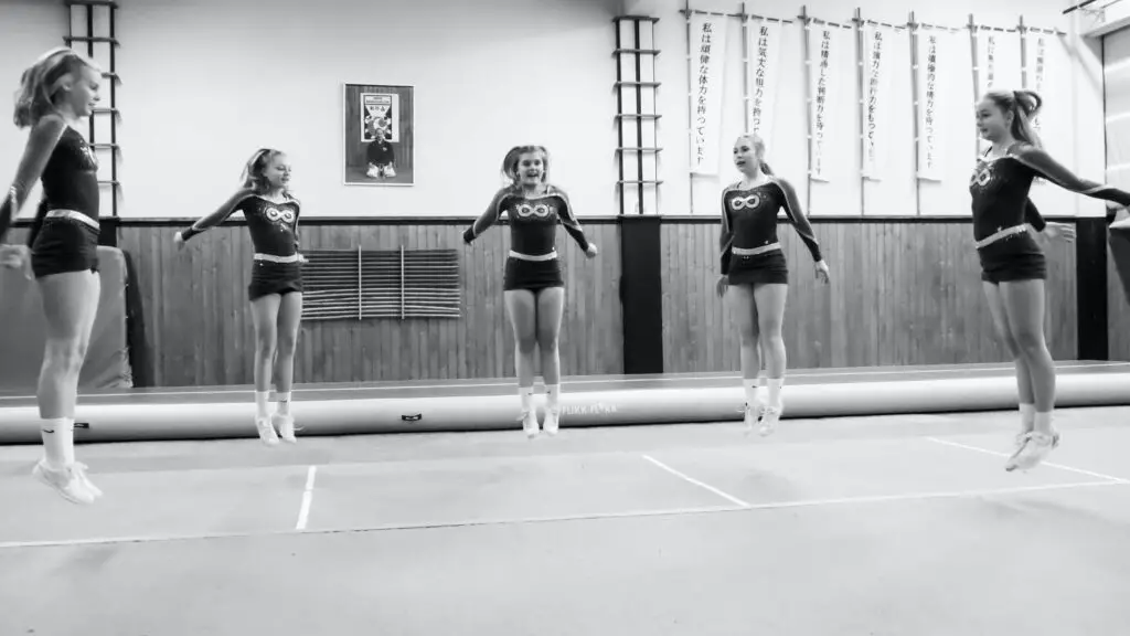 five girls jumping at their cheerleading training, creating cool cheer photo poses