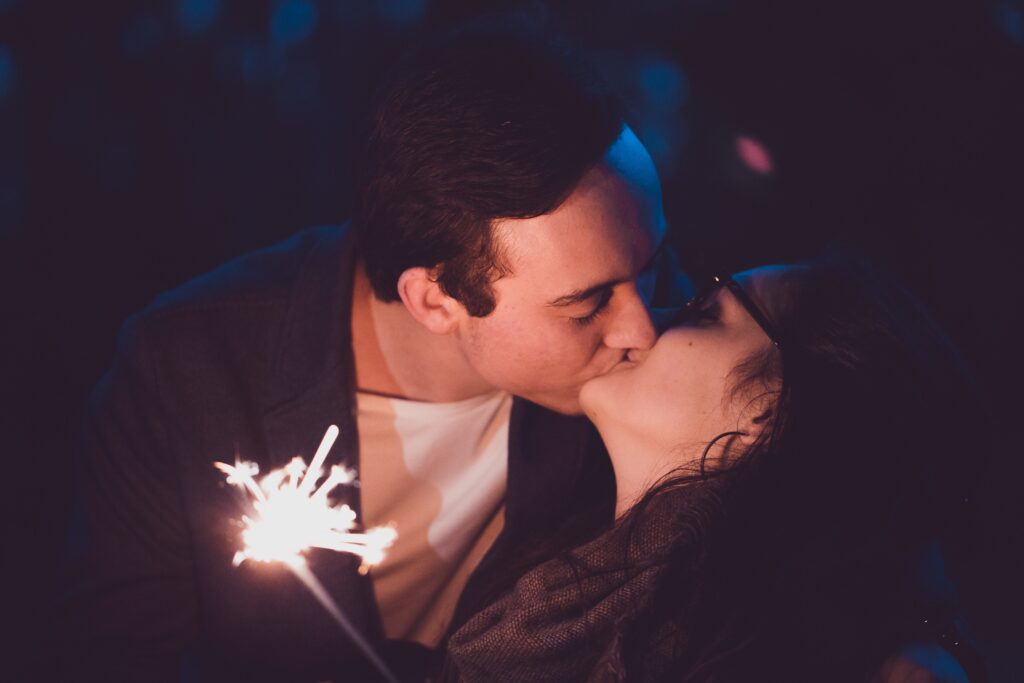 two kissing adults with sparklers to set the mood in their couple photoshoot
