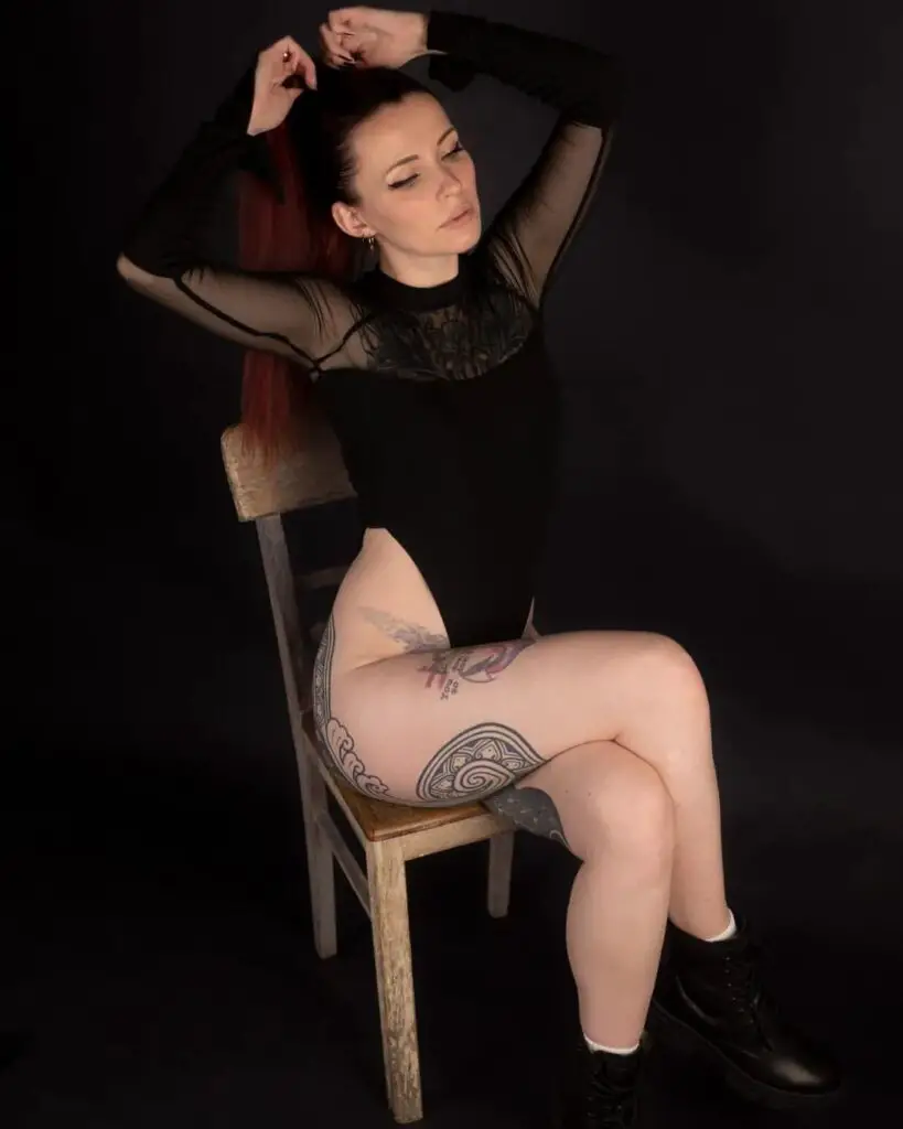 girl doing a sexy pose by putting up her arms, tattooed legs with black emo clothes