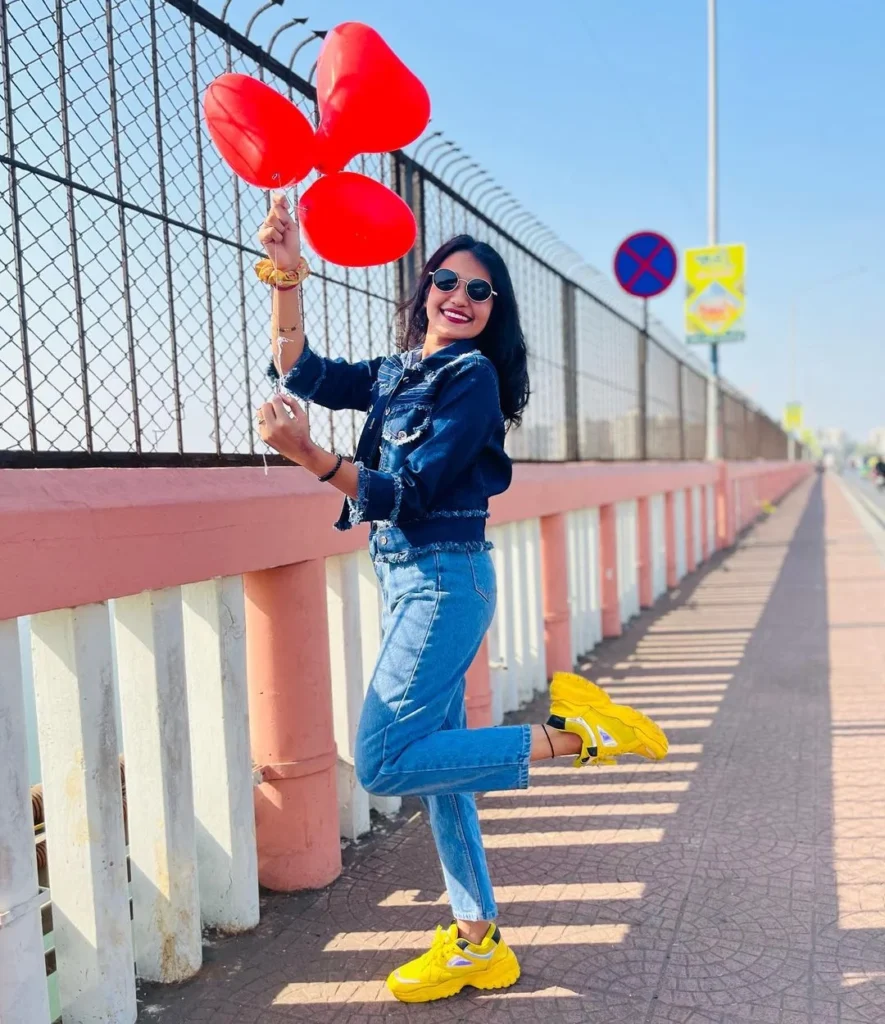 red ballons held by a happy girl doing a striking photo pose towards the camera, next to a street