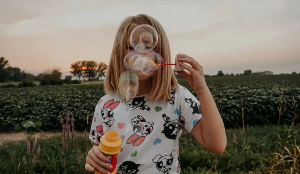 girl blowing bubbles to the camera to hide her face in a portrait photoshoot