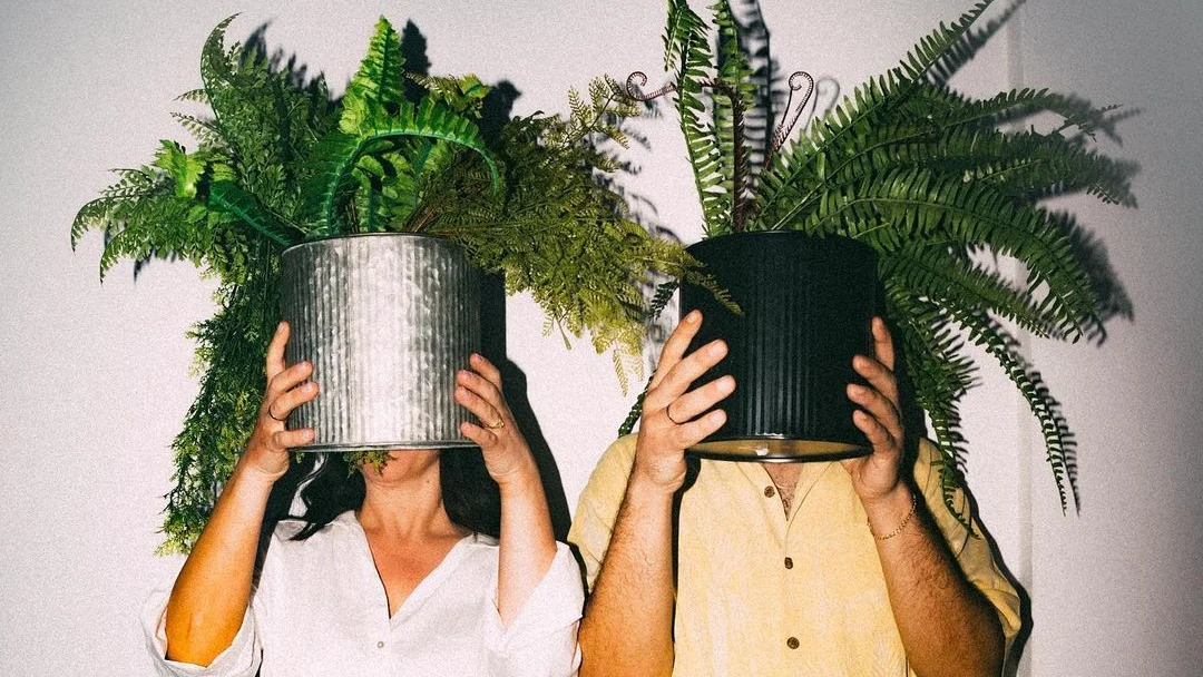 couple holding plants in front of their faces to get a faceless portrait of themselves