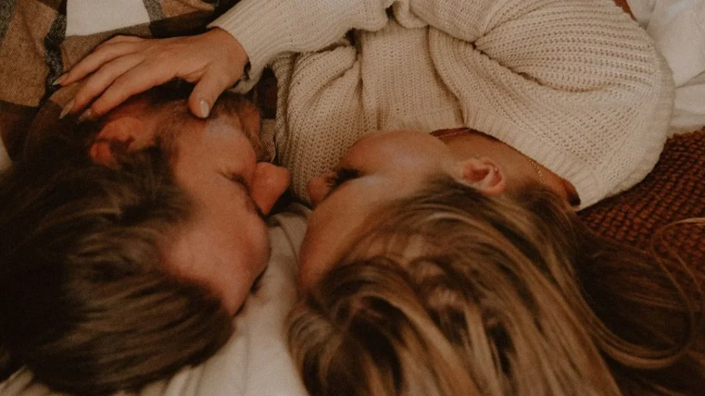 cozy couple snuggling up in bed holding each other while doing a couple fall photoshoot