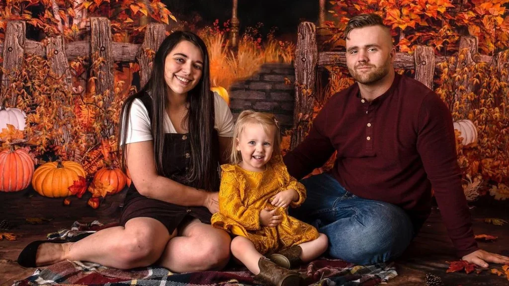 family fall photoshoot in an autumn setting with pumpkins, cute outfits and fall background