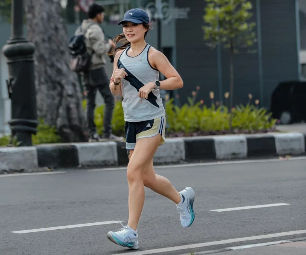asian girl running in sports outfit whilst being taken photos of in the outside