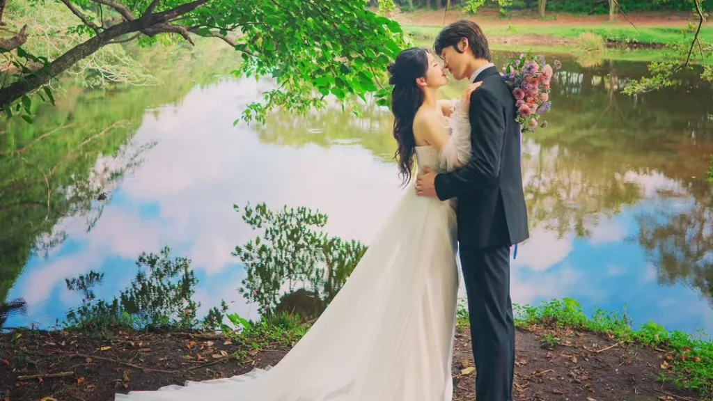 woman and man standing in front of a lake, kissing romantically on there wedding day while being photographed by their photographer for his portfolio