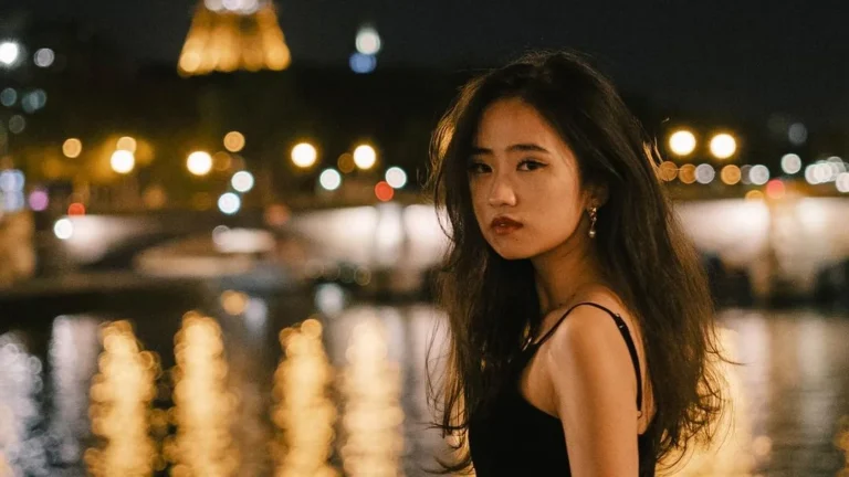 Asian girl posing in front of eiffel tower for night portrait photography at night. Seine as backdrop with nice city lights