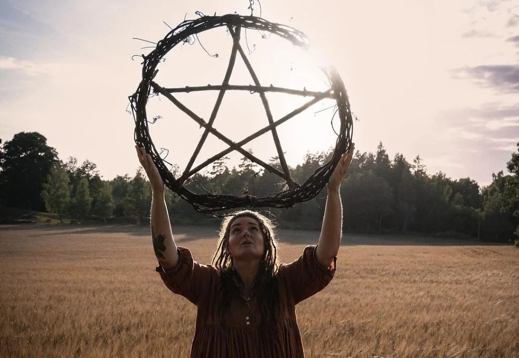 woman holding a pentagram as a wicca symbol to show props for a witchy photoshooting