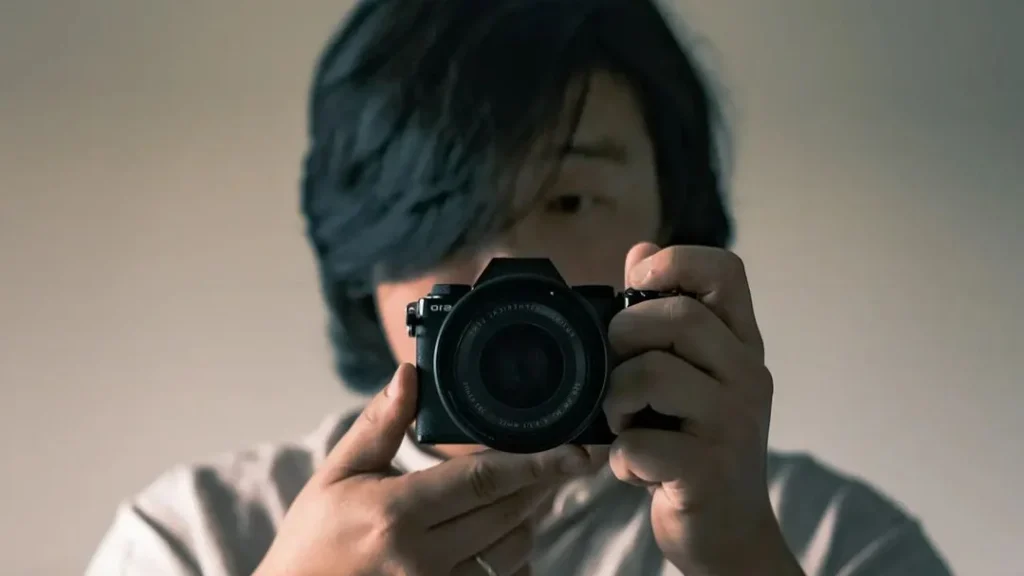 photographer doing a self portrait with his little camera in the mirror, bokeh effect, self portrait