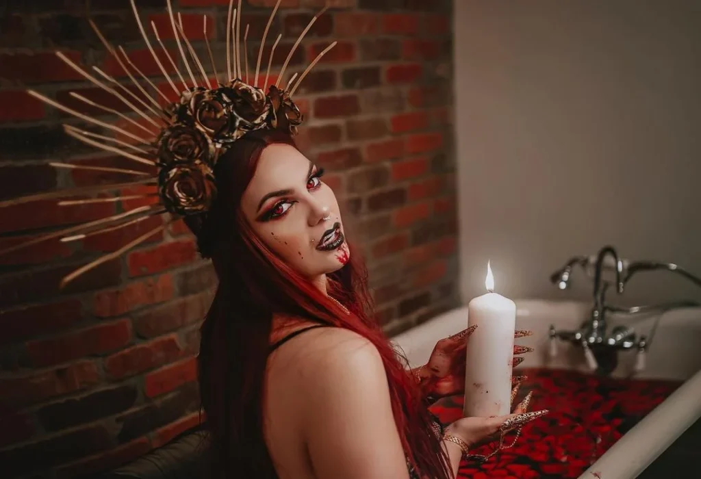 woman in a bathtub holding a white candle, red contact lenses, Fancy head ornament, doing a halloween photoshoot featuring ideas like red roses in the bath