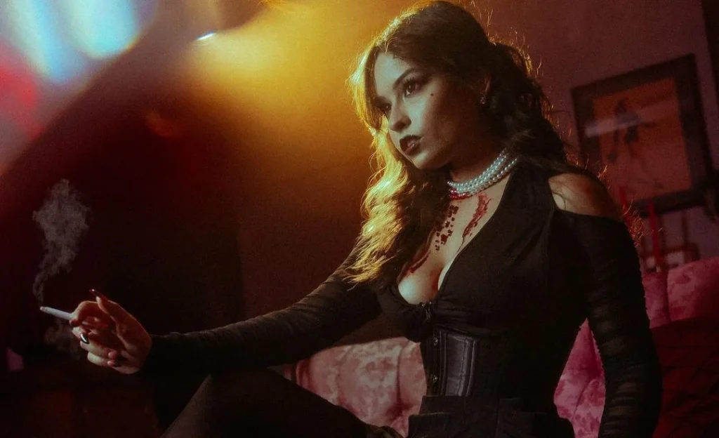 voman holding a cigarette in a gothic halloween outfit with blood on her neck, looking in the distance to create mysterious halloween photography
