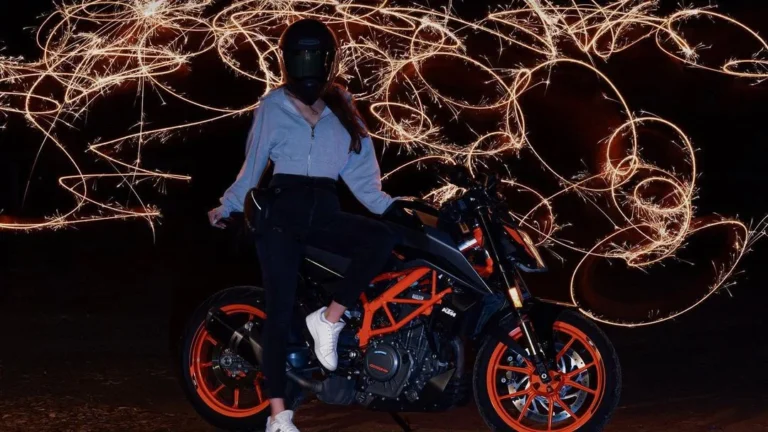 girl posing in front of a motorcycle with cool sparkler effects in the background for new years eve, having cool new year photoshoot ideas