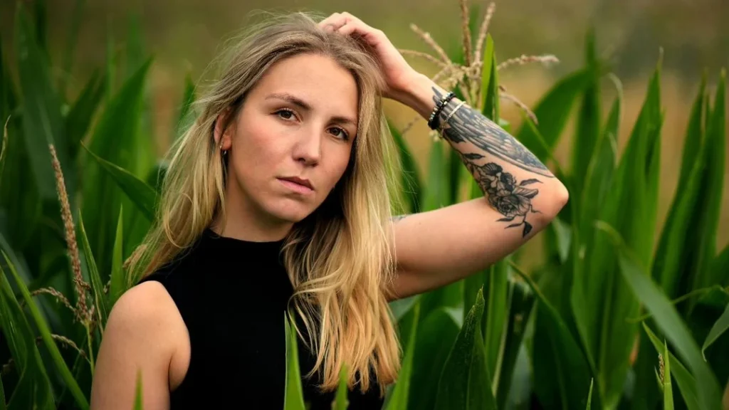 pretty blonde with arm tattoo posing in nature for portrait photography