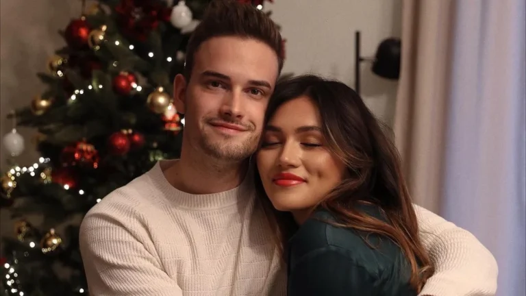 cute couple doing couple christmas photoshoot ideas in front of a christmas tree on christmas eve