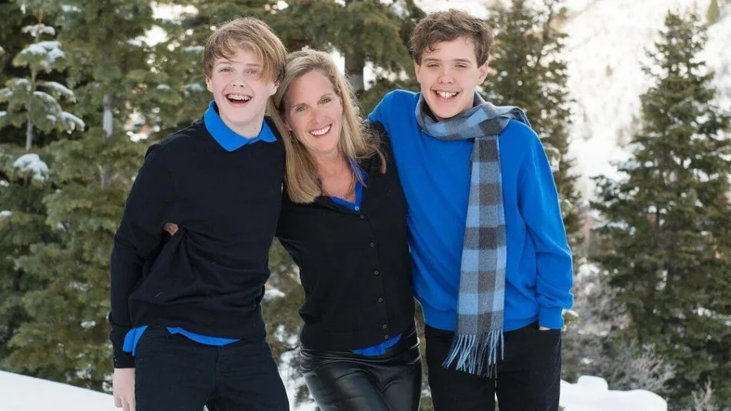 happy family posing in a forest with matching blue family winter outfits for their winter family photoshoot