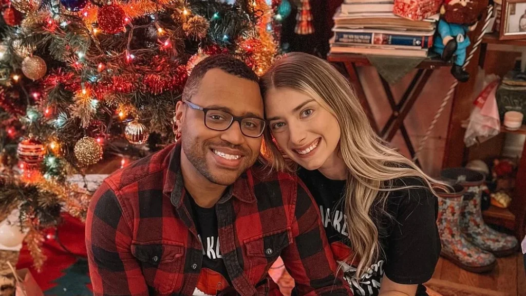cute couple posing in front of their decorated christmas tree, smiling, doing couple christmas photoshoot ideas