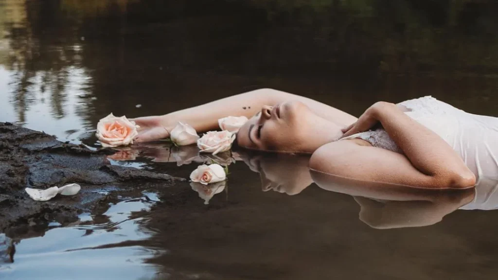 girl posing with roses for boudoir photography with water on a muddy lake