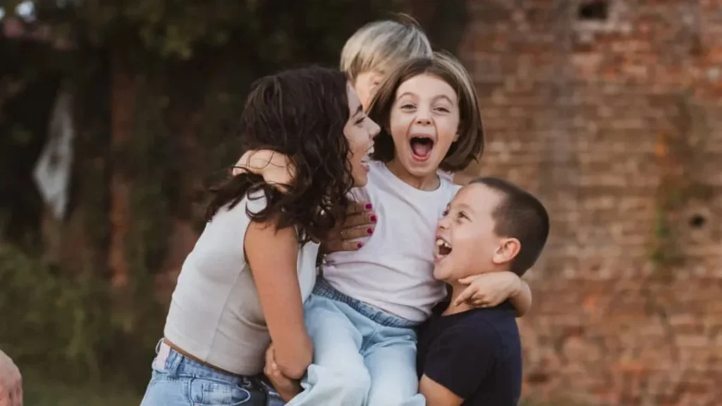 kids hugging and playing with each other, leading to a great family photo with laughing and joy outside