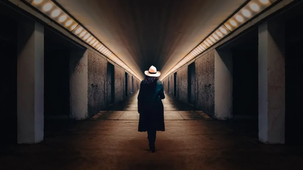 leading lines example with a woman with a hat in a basement, Lights guide the viewer towards the portrait of the woman