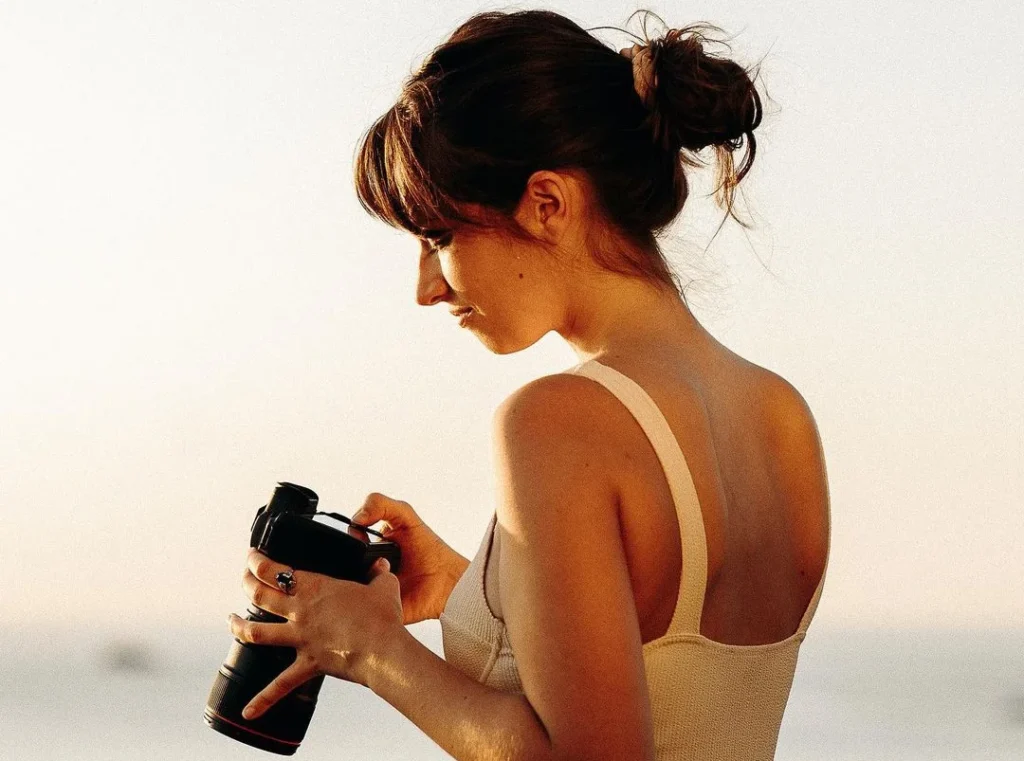 photographer girl looking at her camera, wedding photography packages, brown hair tied to a bun, professional camera