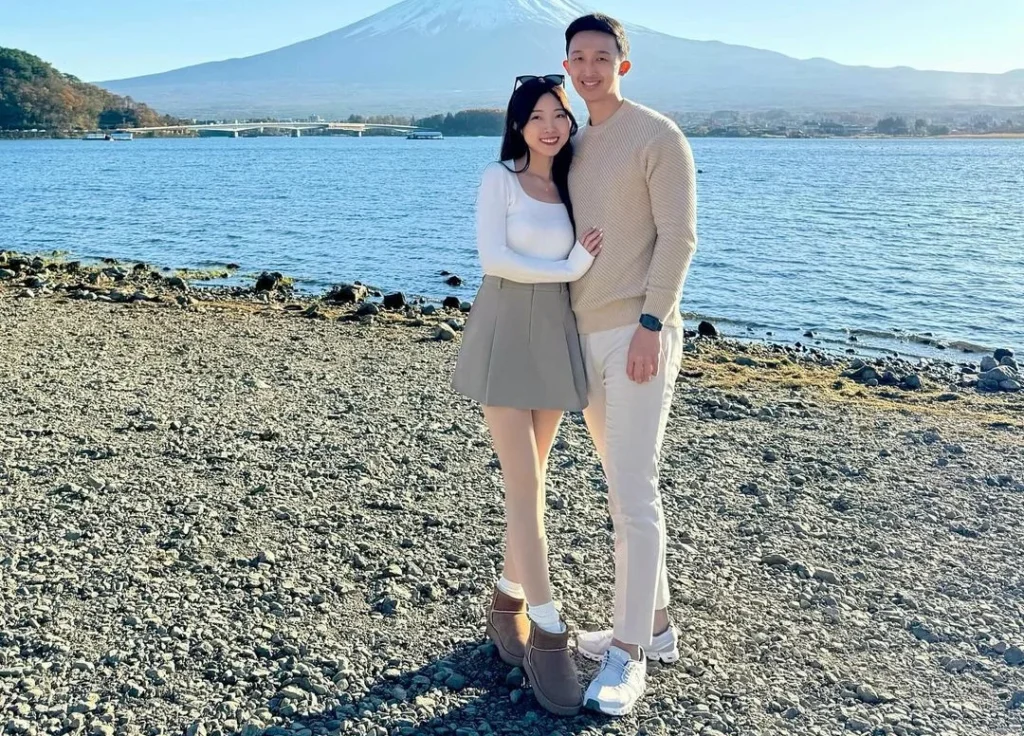 cute asian couple standing in front of a lake and mount fuji in the background, wearing nice outfits and a short skirt