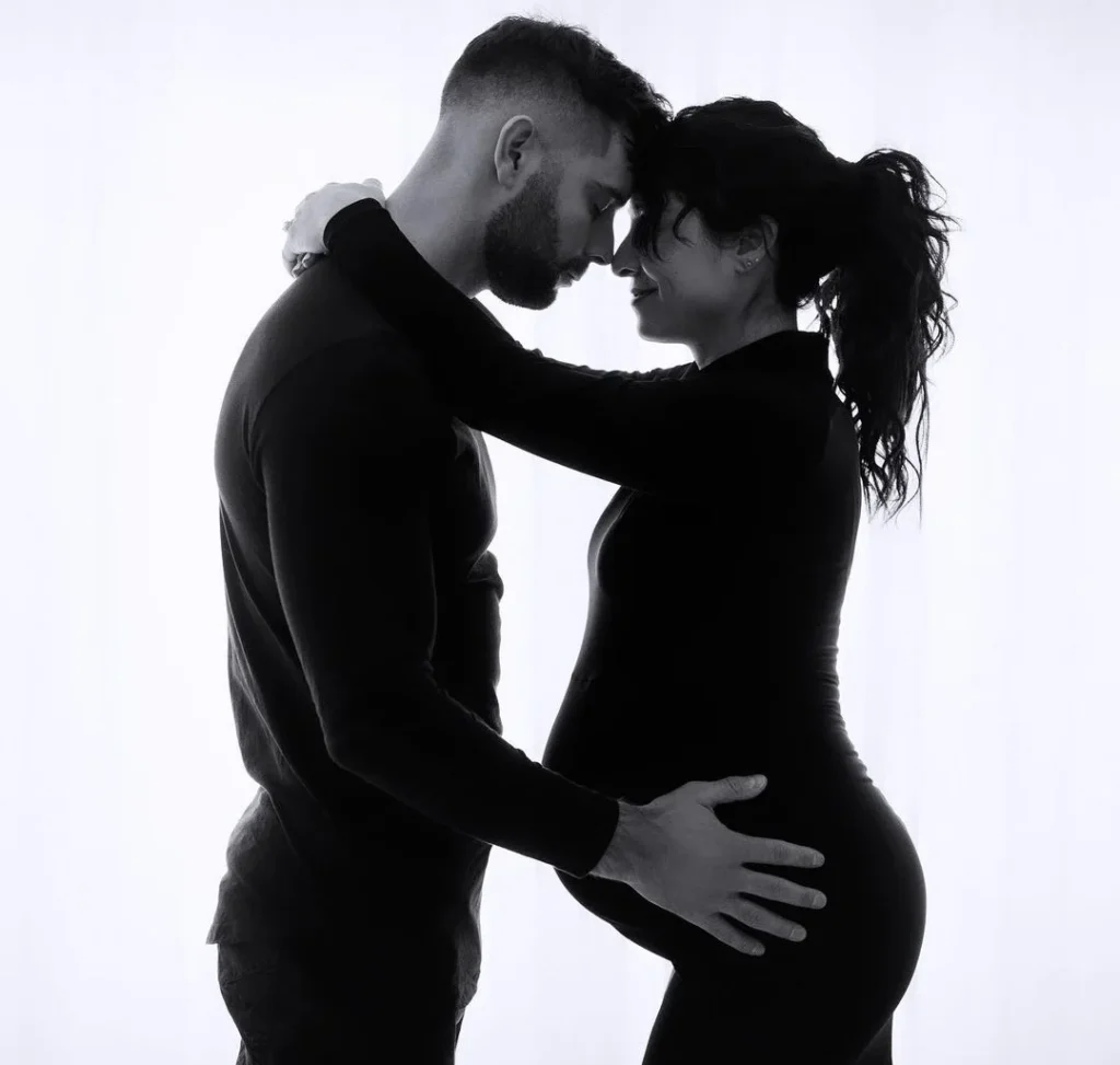 cute couple embracing their pregnancy doing a intimate pregnancy photo pose in a black and white filter