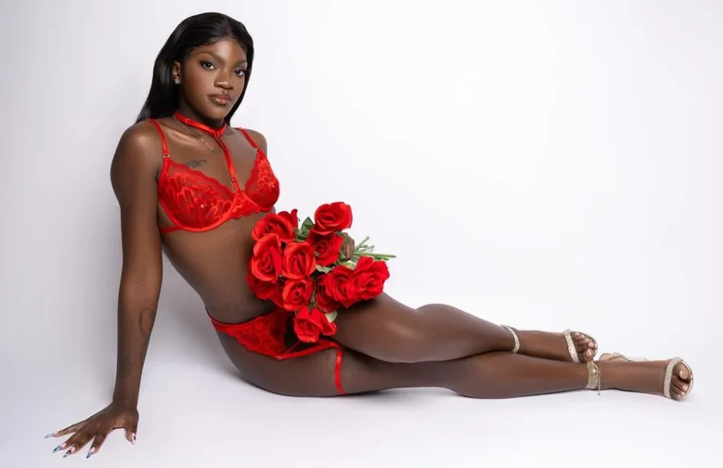 black woman posing for boudoir photography, holding red roses as prop and wearing red matching lingerie