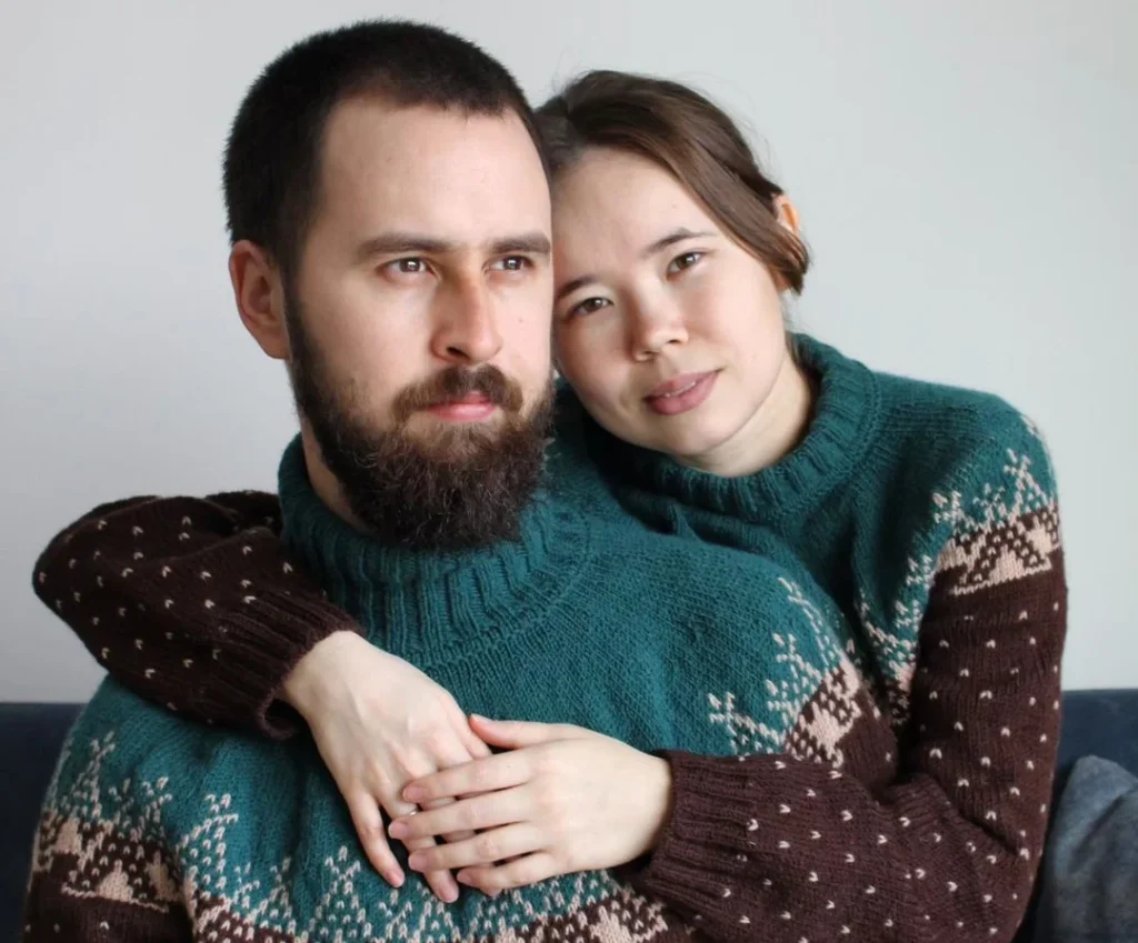 cute couple with asian woman and matching christmas sweaters posing lovely and intimate with their matching couple photoshoot outfits