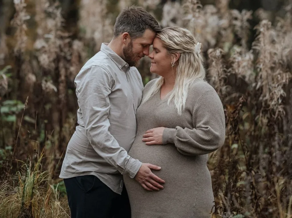 cute couple doing an intimate maternity photo shoot pose while holding their heads to each other 