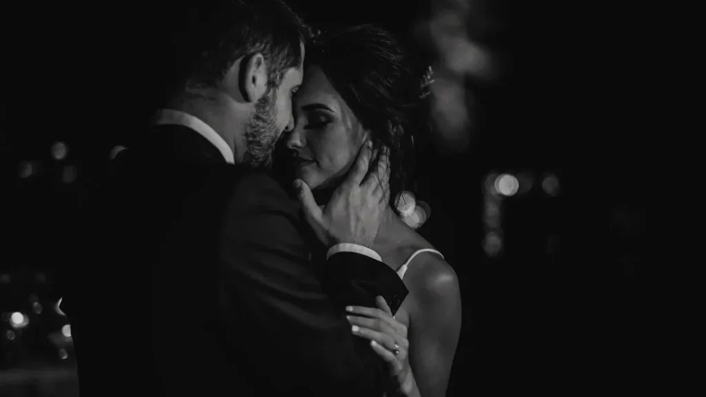 intimate moment of a couple at their wedding kissing and cuddling with each other, creating a romantic and moody moment, black white wedding photography
