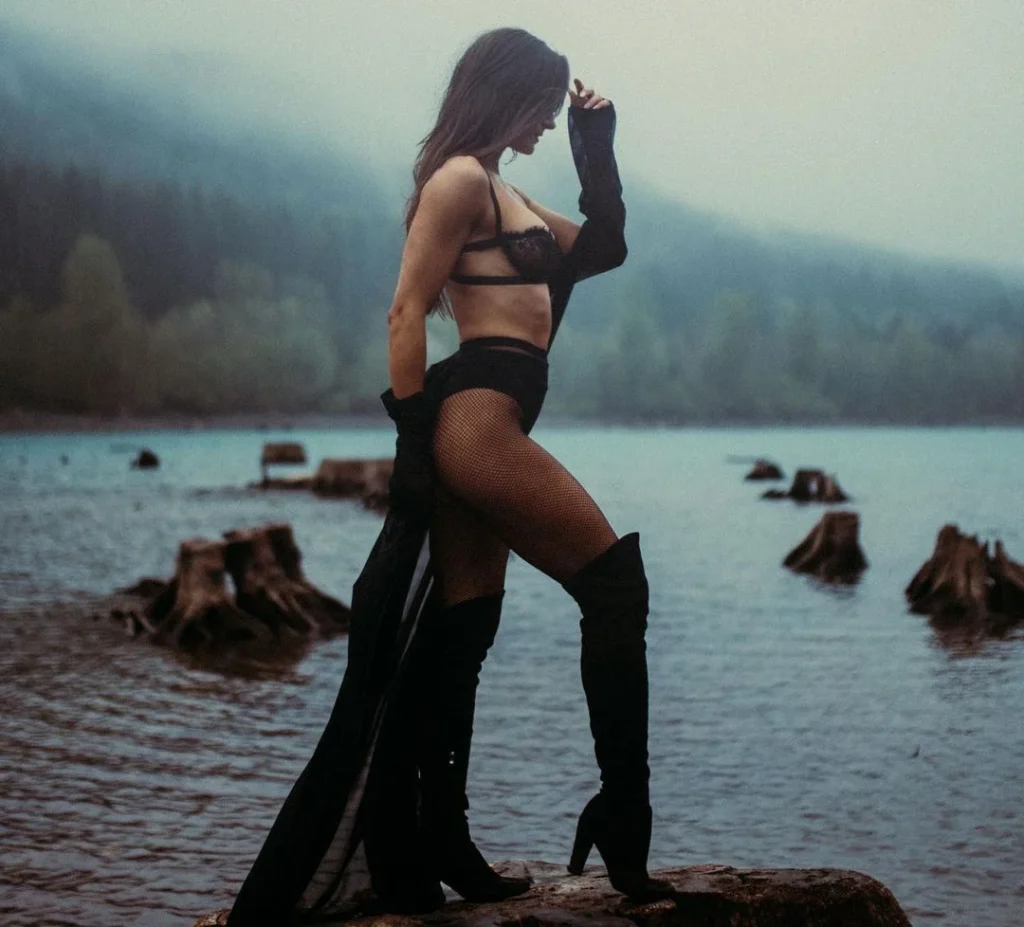 hot woman wearing lingerie at a lake with high stocking boots, posing for boudoir photography outdoor with a long satin clothing