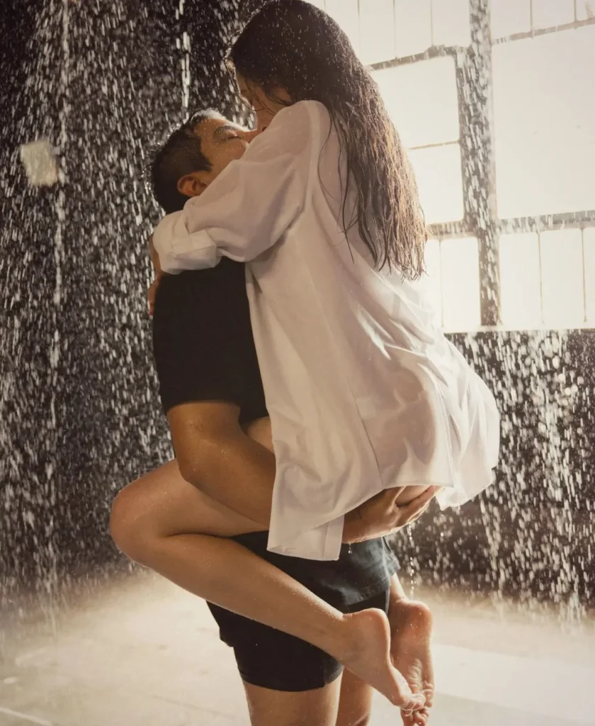 boudoir photoshoot in the rain, the man holding up his girl, kissing her with wet clothes in the rain. Romantic boudoir setting