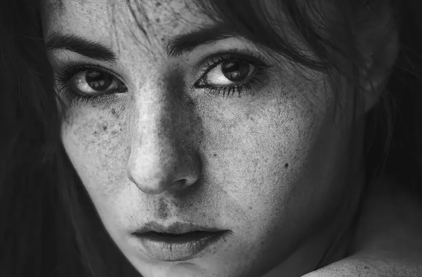 black and white close up photograph of a young woman, looking strongly into the camera, conveying strong emotions in close up portrait photography