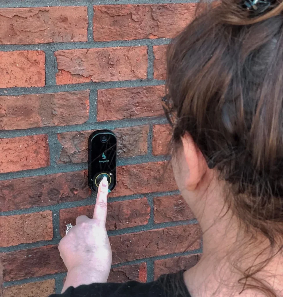 woman ringing at a doorbell camera from amazon on a brick wall, video camera doorbell 
